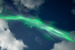 Green aurora borealis dances across a starry night sky.